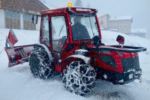 red and black tractor on snow covered ground during daytime